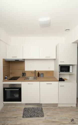 une cuisine avec des armoires blanches et un évier dans l'établissement La résidence Jeanne d'Arc 6, Troyes - France, à Troyes