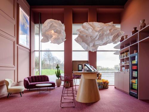 ibis Styles Rotterdam Ahoy في روتردام: غرفة معيشة مع طاولة ونافذة كبيرة