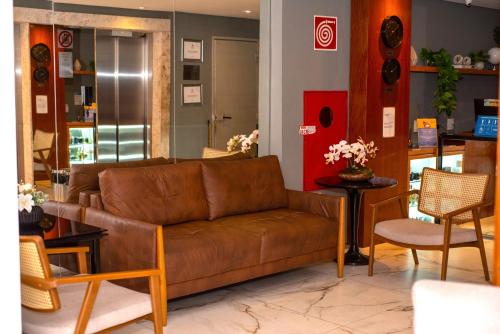 ein Wohnzimmer mit einem braunen Sofa und Stühlen in der Unterkunft Nobile Hotel Juiz de Fora in Juiz de Fora