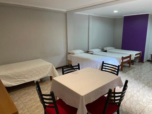 a room with three beds and two tables and chairs at El Tata in Puerto Iguazú