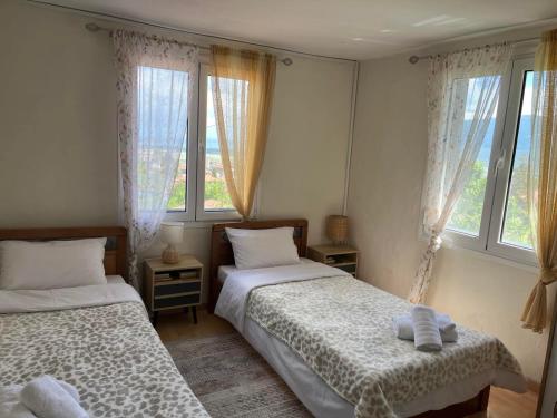 two beds in a room with two windows at Stamoula' s house in Aigáni