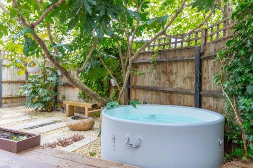 a bath tub in a garden next to a fence at Chic 1BD Maisonette wHot Tub King's Cross! in London