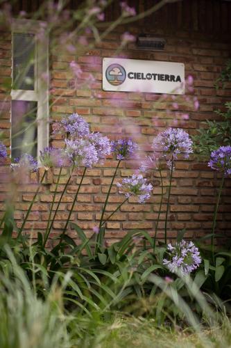 a sign on a brick wall with purple flowers at Cielo de Tierra in Coronel Suárez