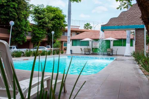 a swimming pool in front of a building with a fountain at Hotel La Quinta Posada Real in Culiacán