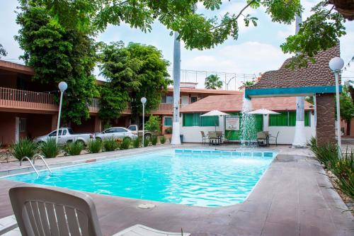 a pool in front of a building with chairs and tables at Hotel La Quinta Posada Real in Culiacán