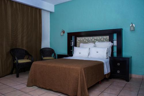 1 dormitorio con 1 cama grande y paredes azules en Hotel La Quinta Posada Real en Culiacán