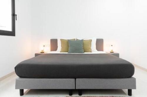 Cama grande en habitación blanca con 2 lámparas en Oriental, en Mindelo