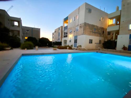 a large blue swimming pool in front of two buildings at Sea view home away from home in St. Paul's Bay