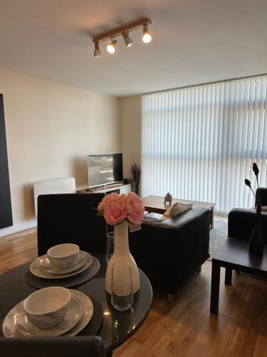 a living room with a table with plates and flowers on it at Cardiff City Center - with FREE Parking in Cardiff