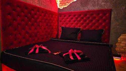 a bedroom with a red bed with shoes on it at Magik Love Apartament in Piła