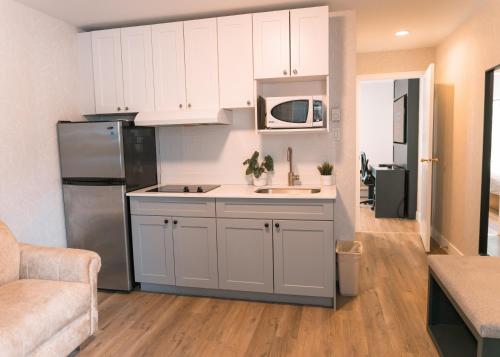 a kitchen with white cabinets and a stainless steel refrigerator at Hotel Civilia Lakeside by Civilia Golf Retreat in Clearwater