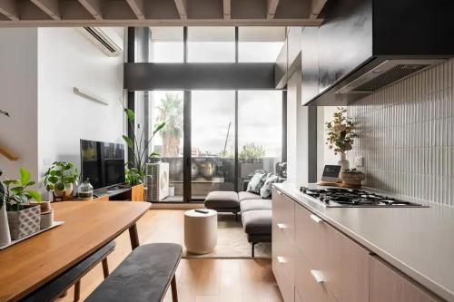 a kitchen with a table and a stove top oven at Centrally Located Modern Loft w Free Parking, Infinity Pool, Workspace in Melbourne
