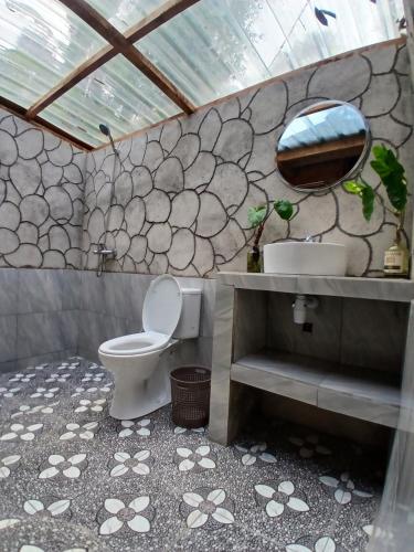 a bathroom with a toilet and a sink and a mirror at MY HOME tetebatu in Tetebatu