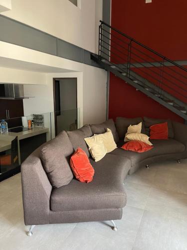 a gray couch with colorful pillows sitting in a living room at Departamento Torre Onze in Mérida