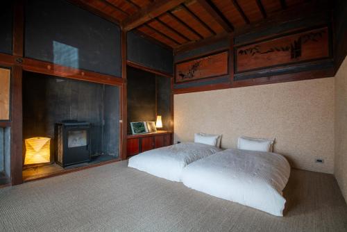 um quarto com uma cama branca e uma lareira em 古民家宿コロク-Kominka Stay Koroku- em Fujimi