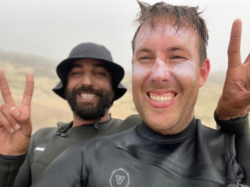 two men in wet suits giving the peace sign with their hands at W Surf Morocco in Agadir