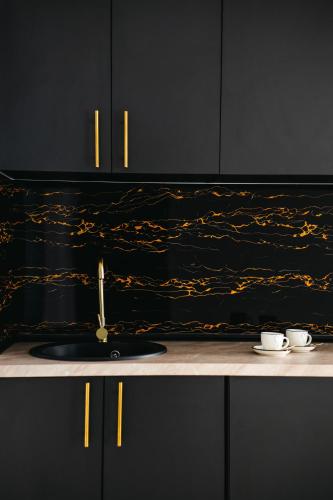 a black kitchen with a sink and two cups at Modern Lux Apartment 3 in Brčko