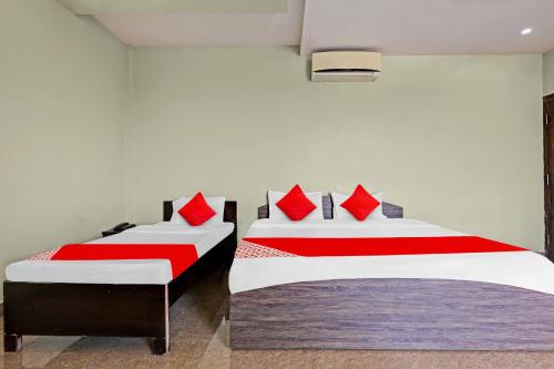 2 Betten mit roten Kissen in einem Zimmer in der Unterkunft SPOT ON 81091 Gmall in Haldwani-Kathgodam