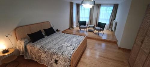 a bedroom with a bed and two chairs at Apartamentos El Xardín in Cabrafigal