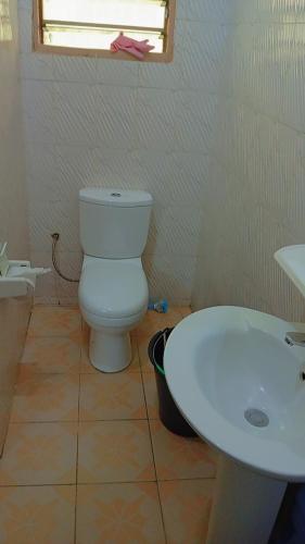 a bathroom with a white toilet and a sink at Timba coquette-loge in Cotonou