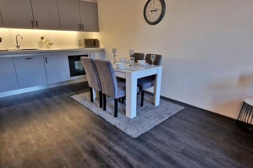 a kitchen with a table with chairs and a clock on the wall at Modern 1 Bed Apartment With Secure Gated Parking in Bradford