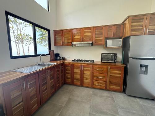 a kitchen with wooden cabinets and a stainless steel refrigerator at Canavida Villas & Resort in Uvita