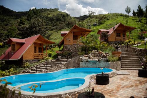 a resort with a swimming pool in front of houses at Lodge la Arboleda de Paz in Oxapampa