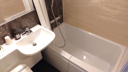 a bathroom with a sink and a toilet and a bath tub at Handa Station Hotel in Handa
