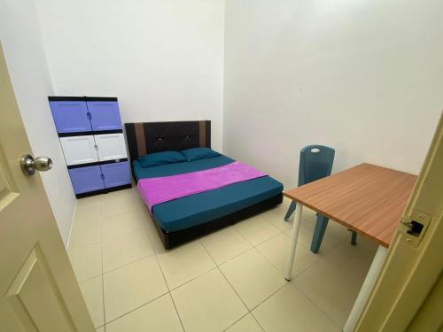 um pequeno quarto com uma cama e uma mesa em Homestay Cikgu Ahmed Batu Kikir em Batu Kikir
