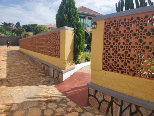 a fence with a brick walkway next to a house at Alice Gardens & Campsite in Entebbe
