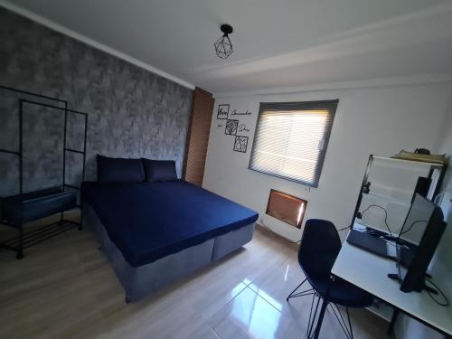 a bedroom with a blue bed and a desk and a television at Apartamento Recreio p12 in Rio de Janeiro