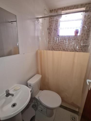 a bathroom with a toilet and a sink and a window at Apartamento Recreio p12 in Rio de Janeiro