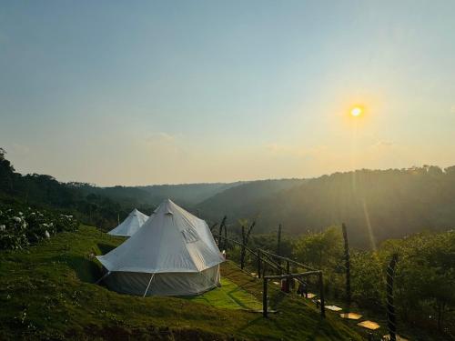 two tents on a hill with the sun in the background at Glamping Việt Úc in Kon Von Kla