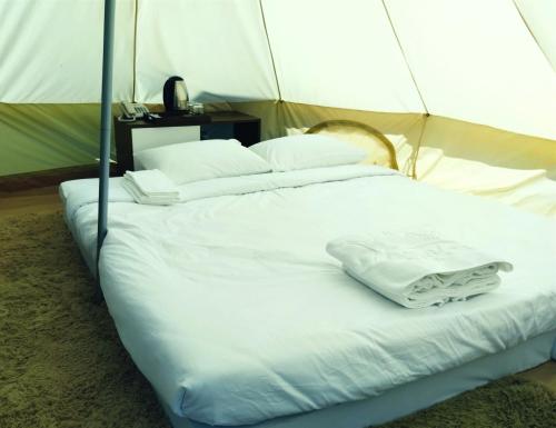 a bed with white sheets and pillows in a tent at Glamping Việt Úc in Kon Von Kla