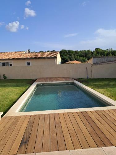 une piscine avec une terrasse en bois et une maison dans l'établissement Villa SOFIA, à Saint-Saturnin-lès-Apt