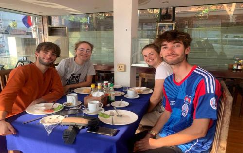 a group of people sitting at a table with a blue table cloth at Blossoming Romduol Boutique in Siem Reap