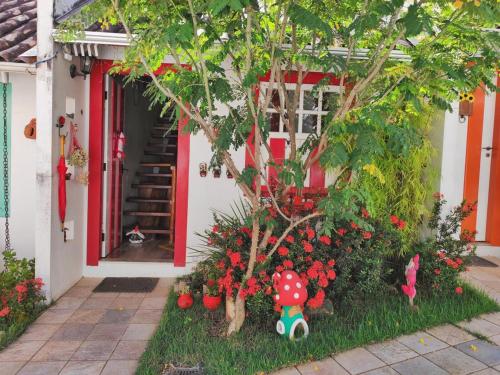 a house with a tree and flowers in front of it at CasinhaPiri in Pirenópolis