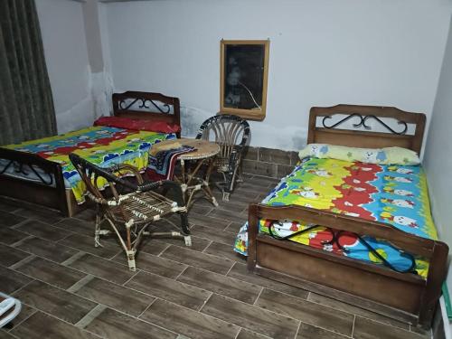 a bedroom with two beds and a table and chairs at شاليه سياحي مكيف صف أول علي البحر مباشره ومكيف وبحديقه خاصه in Ras Sedr
