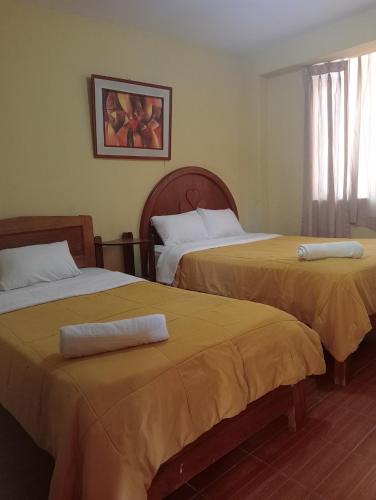2 Betten in einem Hotelzimmer mit Handtüchern darauf in der Unterkunft Hotel San Eduardo in Chiclayo