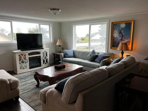 sala de estar con sofá y TV en Idlewild Manor Vacation home, en Gold Beach
