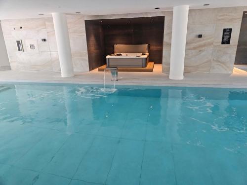 a large swimming pool in a building with a table at JOY MONTEVIDEO - Apartamento Premium - Servicios de Hotel 5 Estrellas in Montevideo