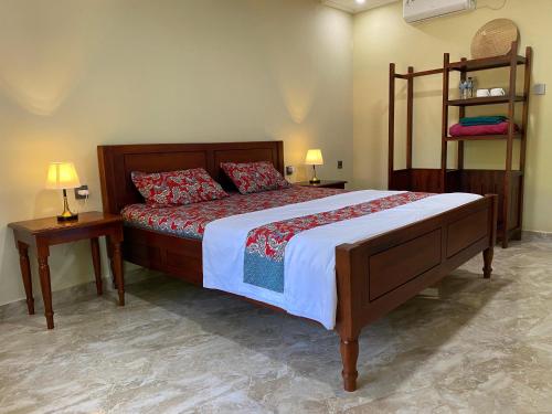 a bedroom with a large bed with two tables and two lamps at Mango Guesthouse in Pangandaran