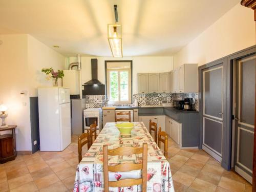 - une cuisine avec une grande table, des chaises et un réfrigérateur dans l'établissement Gîte familial avec jardin dans un ancien corps de ferme au cœur de la Dordogne - FR-1-616-374, à Saint-Chamassy