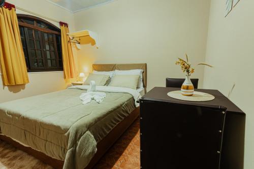 a bedroom with a bed and a dresser with a table at Pousada São Benedito in Santo Antônio do Pinhal
