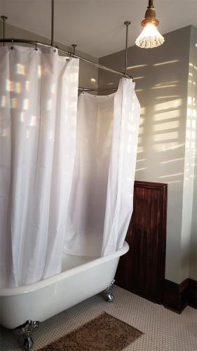 a bath tub with a white shower curtain in a bathroom at The Eleanor Davis House in Hannibal