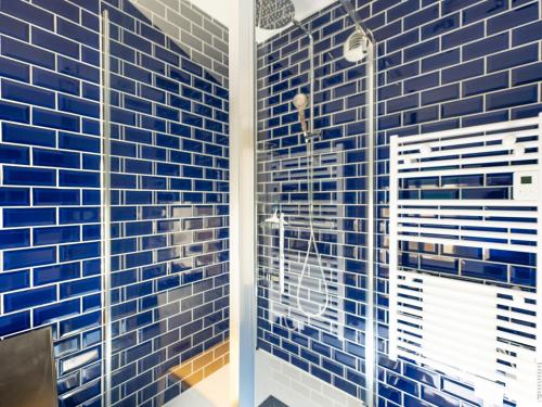 La salle de bains est pourvue de carrelage bleu et d'une douche. dans l'établissement Appartement rénové 3 étoiles, centre baie des Sables d'Olonne, climatisé, 2 pièces, garage privé - FR-1-197-595, à Les Sables-dʼOlonne