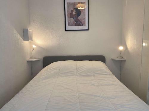 - un lit dans une chambre avec deux lumières sur le mur dans l'établissement Bel Appartement T1 avec Loggia à Balaruc-les-Bains - FR-1-553-254, à Balaruc-les-Bains
