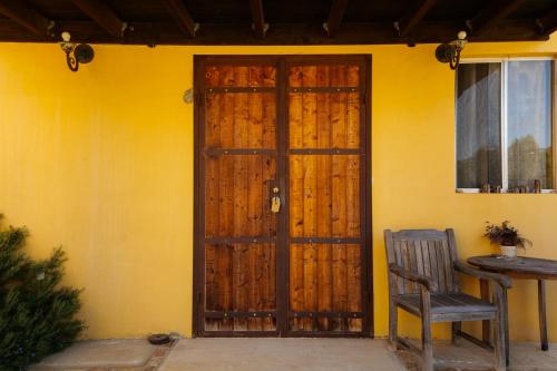 a wooden door to a yellow house with a chair at Quinta Estrella in Valle de Guadalupe