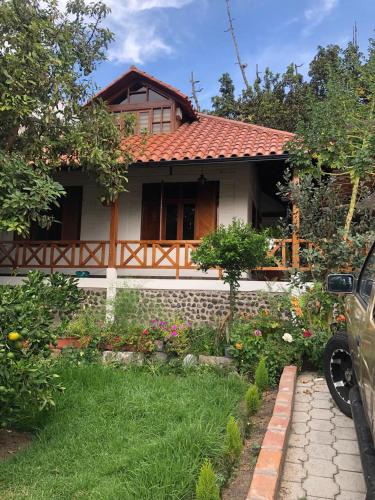 a house with a garden and a car parked in front of it at CASA DE CAMPO HOSPEDAJE in Ambato