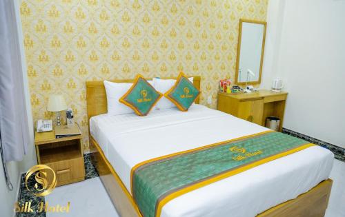 - une chambre avec un grand lit et un miroir dans l'établissement Silk Hotel near Tan Son Nhat Airport, à Hô-Chi-Minh-Ville